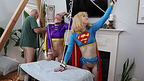 Batgirl and Supergirl endure intense forced climaxes together