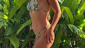 pretty brunette in tropical bikini dances in garden