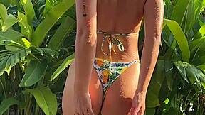 pretty brunette in tropical bikini dances in garden