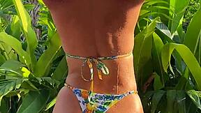 pretty brunette in tropical bikini dances in garden
