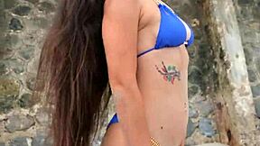 petite brunette flashes sexy body in tiny blue bikini on crowded beach