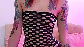 Tattooed redhead model poses in fishnet stockings creatively