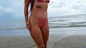 Petite brunette walks the beach in a sexy bikini enjoying public fun